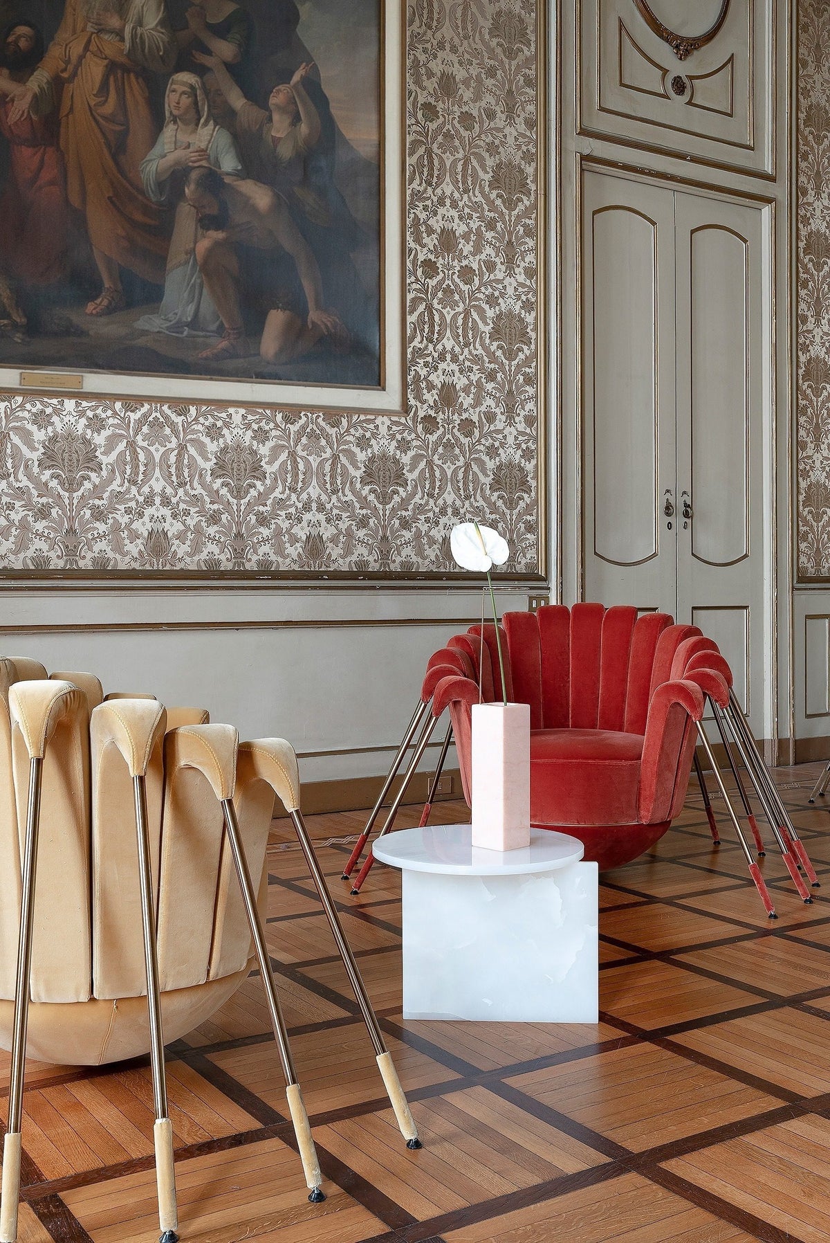 Origin Side Table in white stone beside a red scallop chair