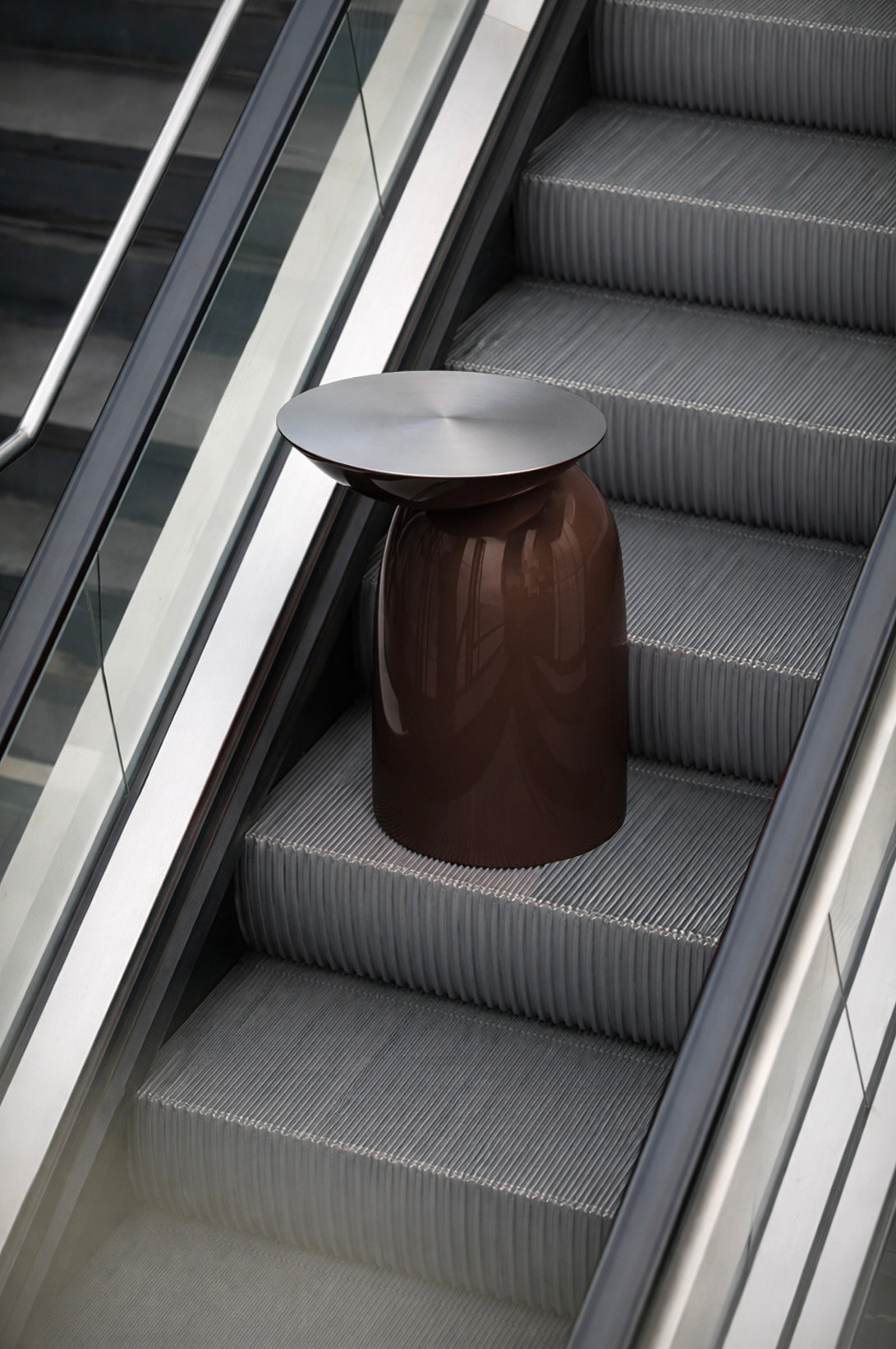 Pingu Side Table in brown high-gloss lacquer staged on an escalator