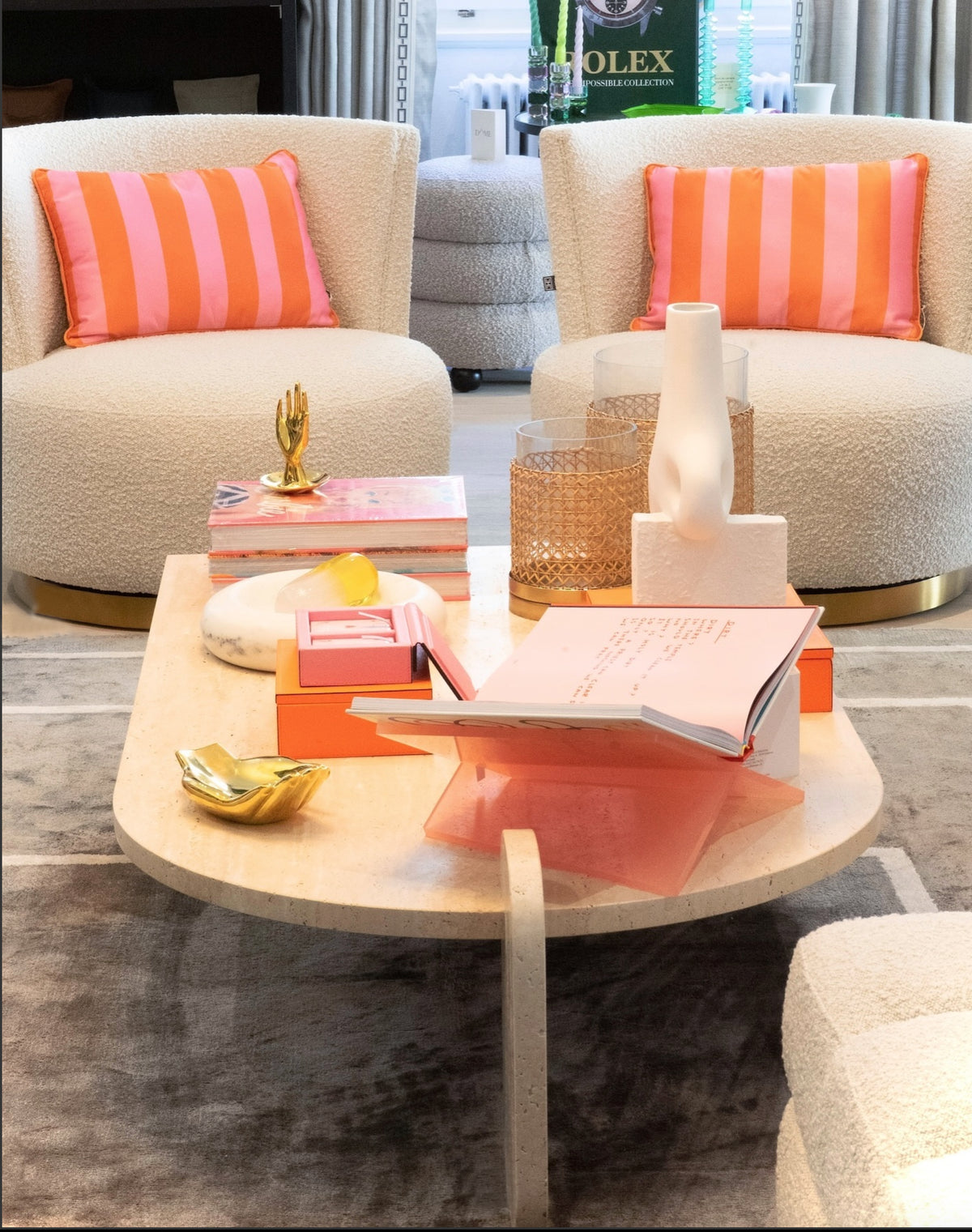 Playing Games Travertine Coffee Table styled with orange books between bouclé armchairs