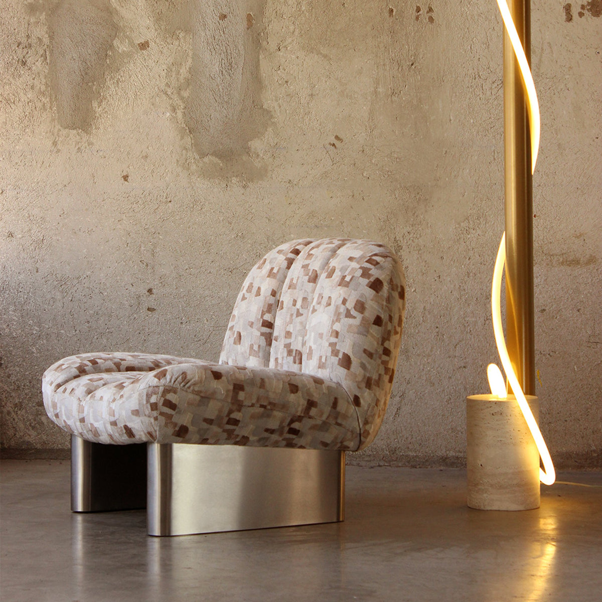 Colin Armchair in geometric jacquard with metal base beside a glowing floor light, side view
