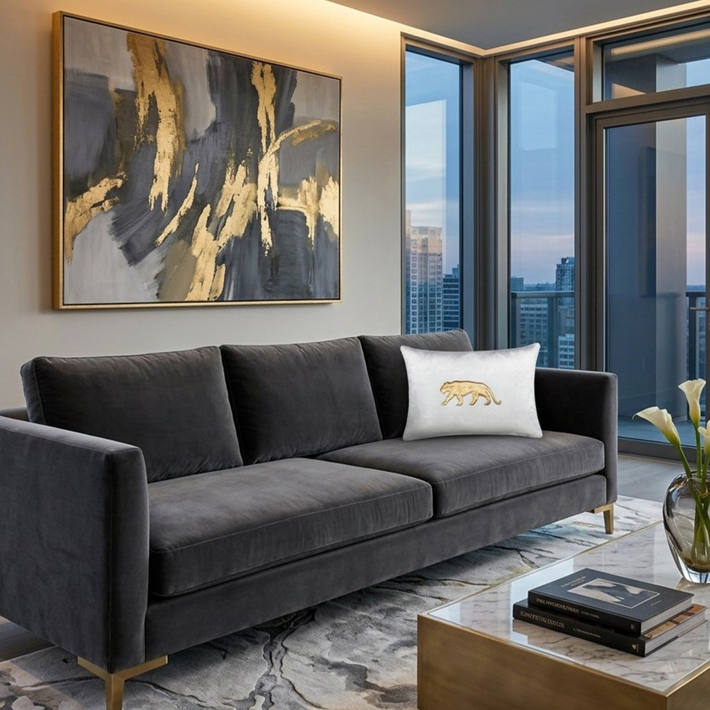 Rica Embroidered Pillow Lumbar in Ivory Gold on a grey velvet sofa in a high-rise living room