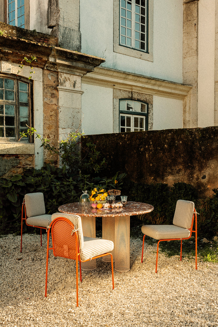 Riviera Chairs around a terrazzo pillar table in a garden courtyard