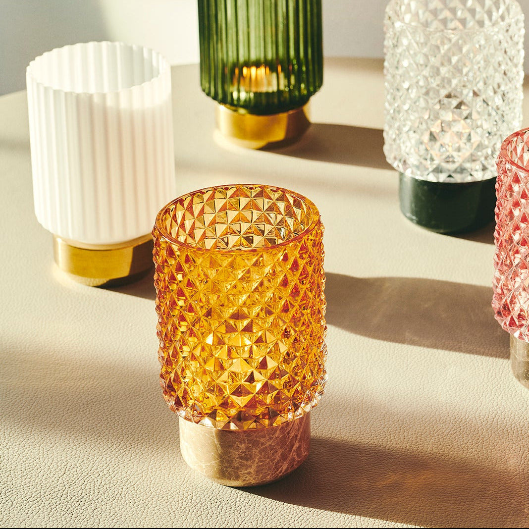 Sons of Marble Candle holder hurricane in Amber, close-up with marble base beside white and green glass
