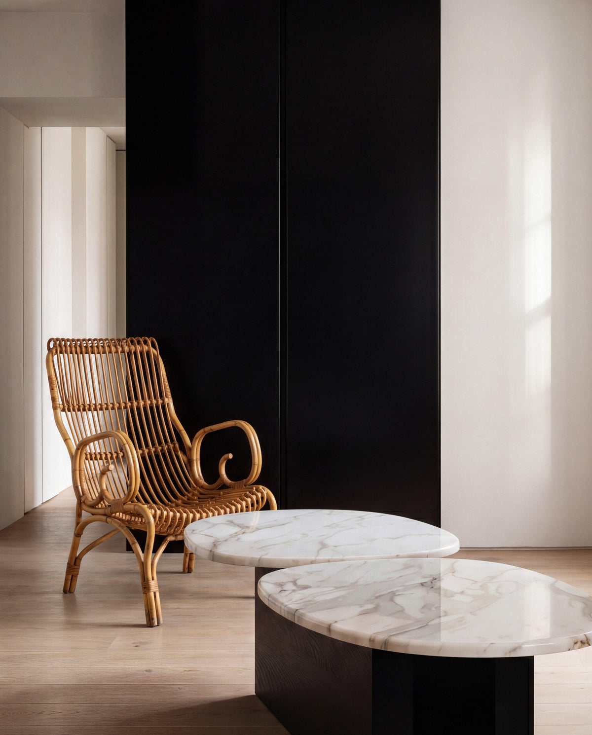 Taras Coffee Table with white marble tops on a black base beside a rattan armchair