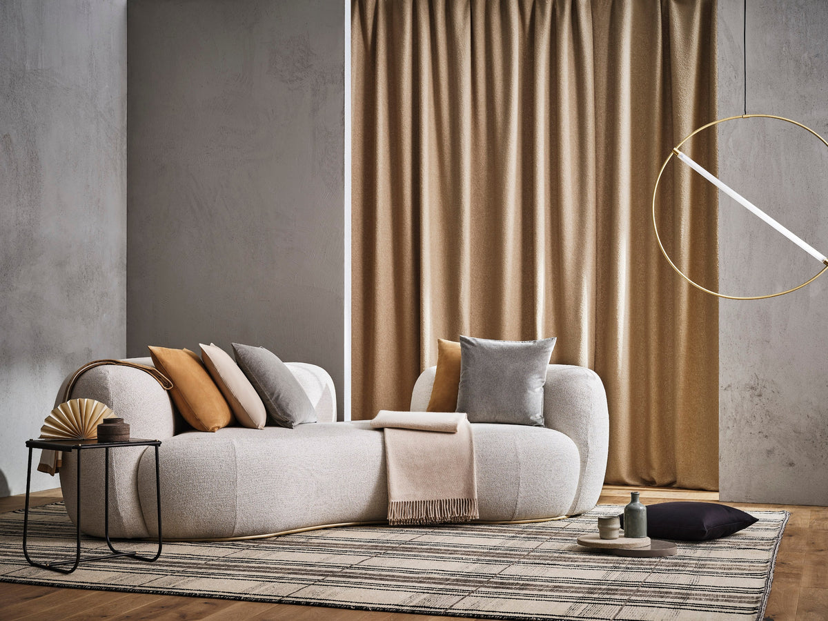 Tateyama Cloud Sofa in cream bouclé with orange pillows by a tan curtain