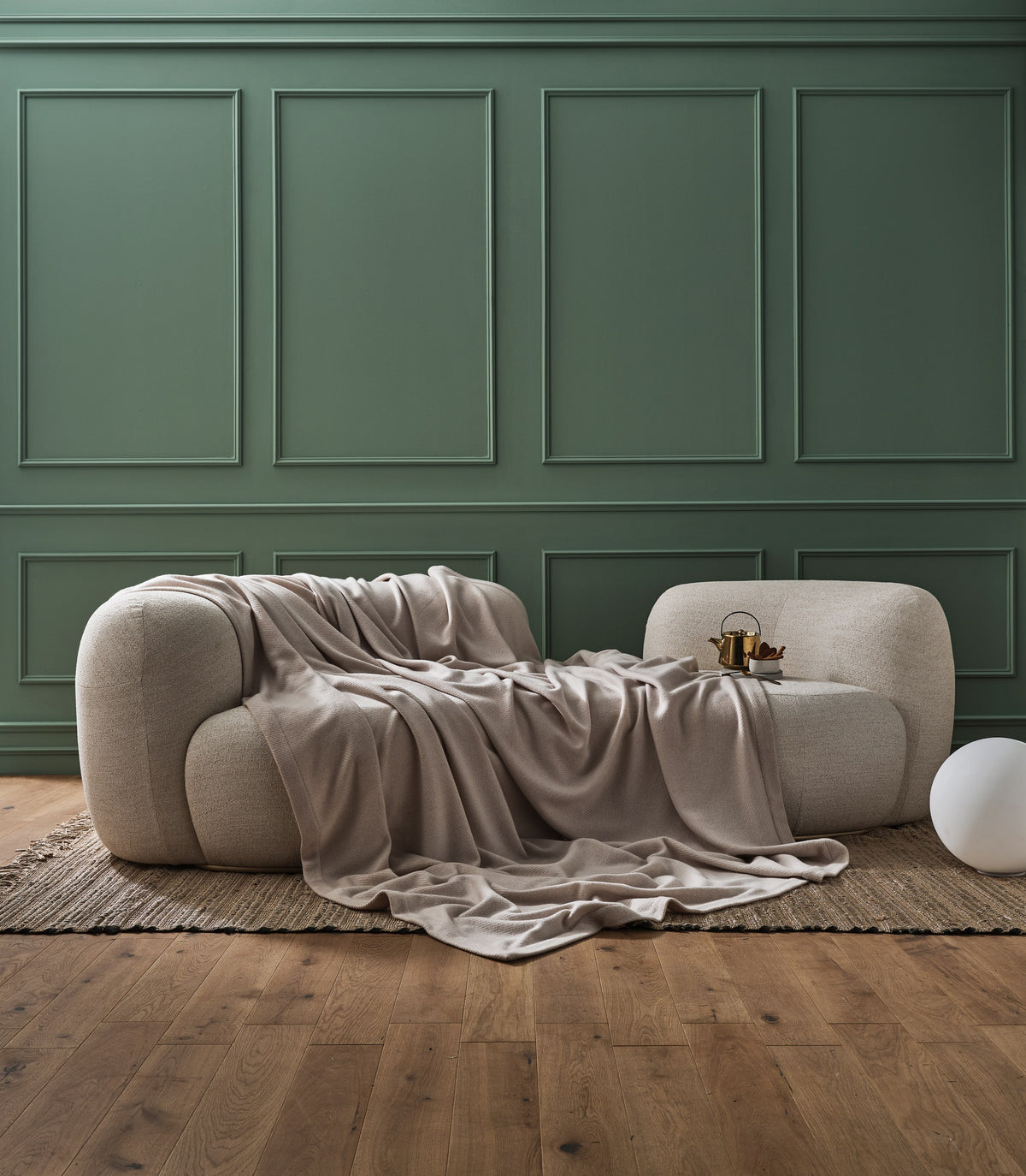 Tateyama Cloud Sofa in ivory with a draped throw against a green paneled wall