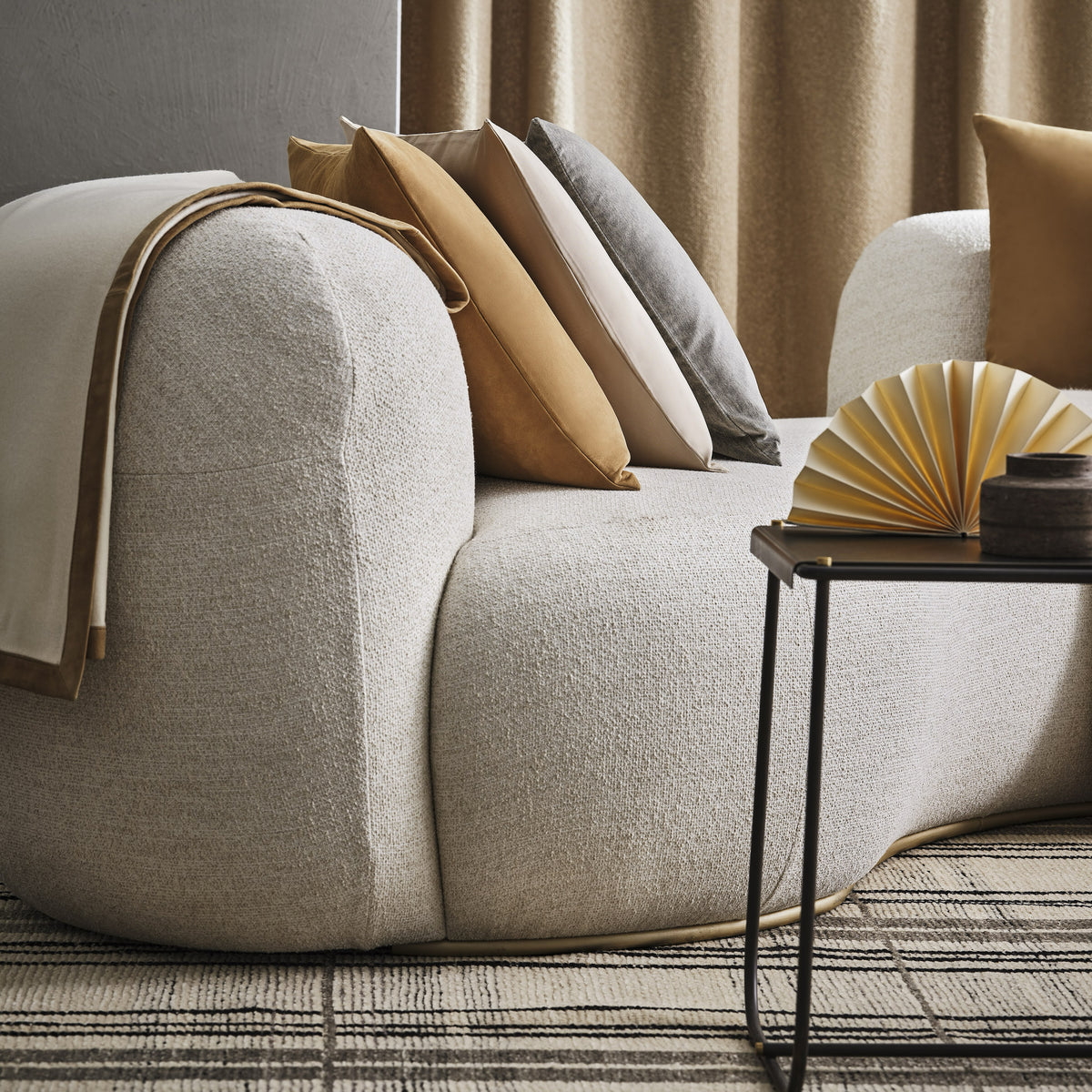 Tateyama Cloud Sofa arm with stacked pillows and a fan beside a side table