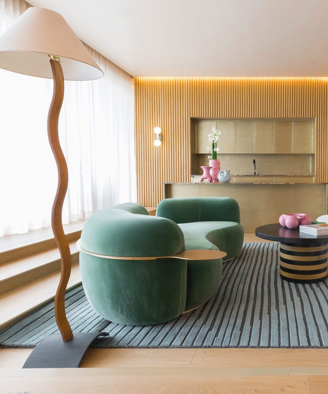 Tateyama Curved Sofa in green velvet with a wavy floor lamp in a wood-panelled room