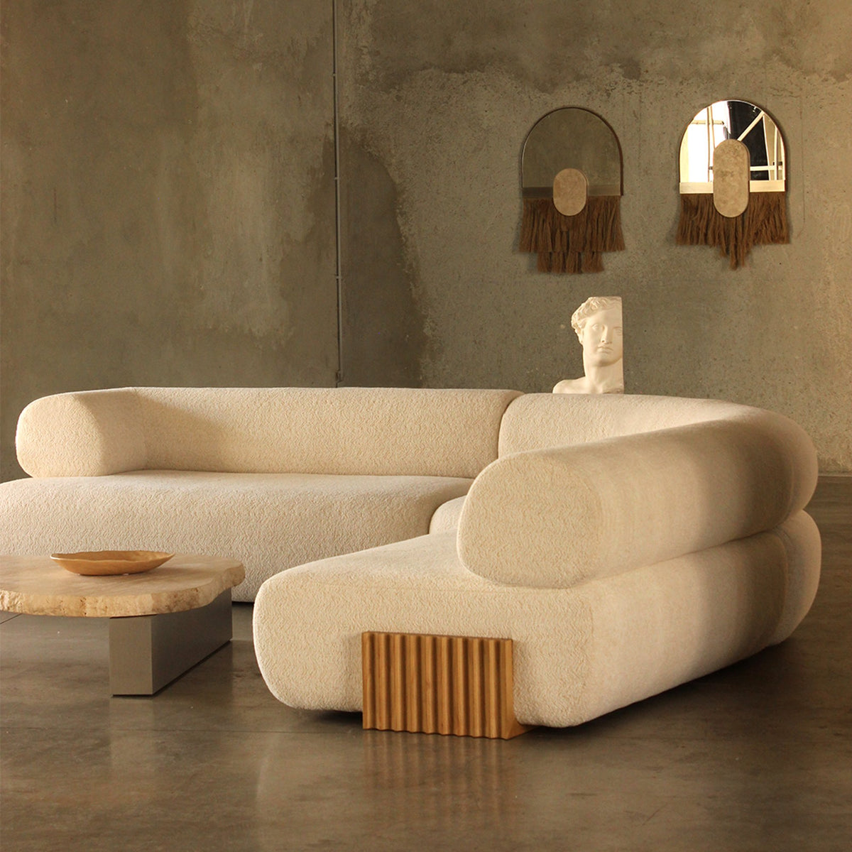 Carmel Ottoman shown with matching cream boucle modular seating in a concrete room