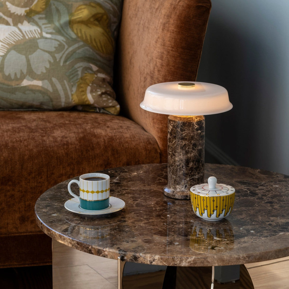Trip 2 Table Lamp on a marble side table beside a rust velvet sofa