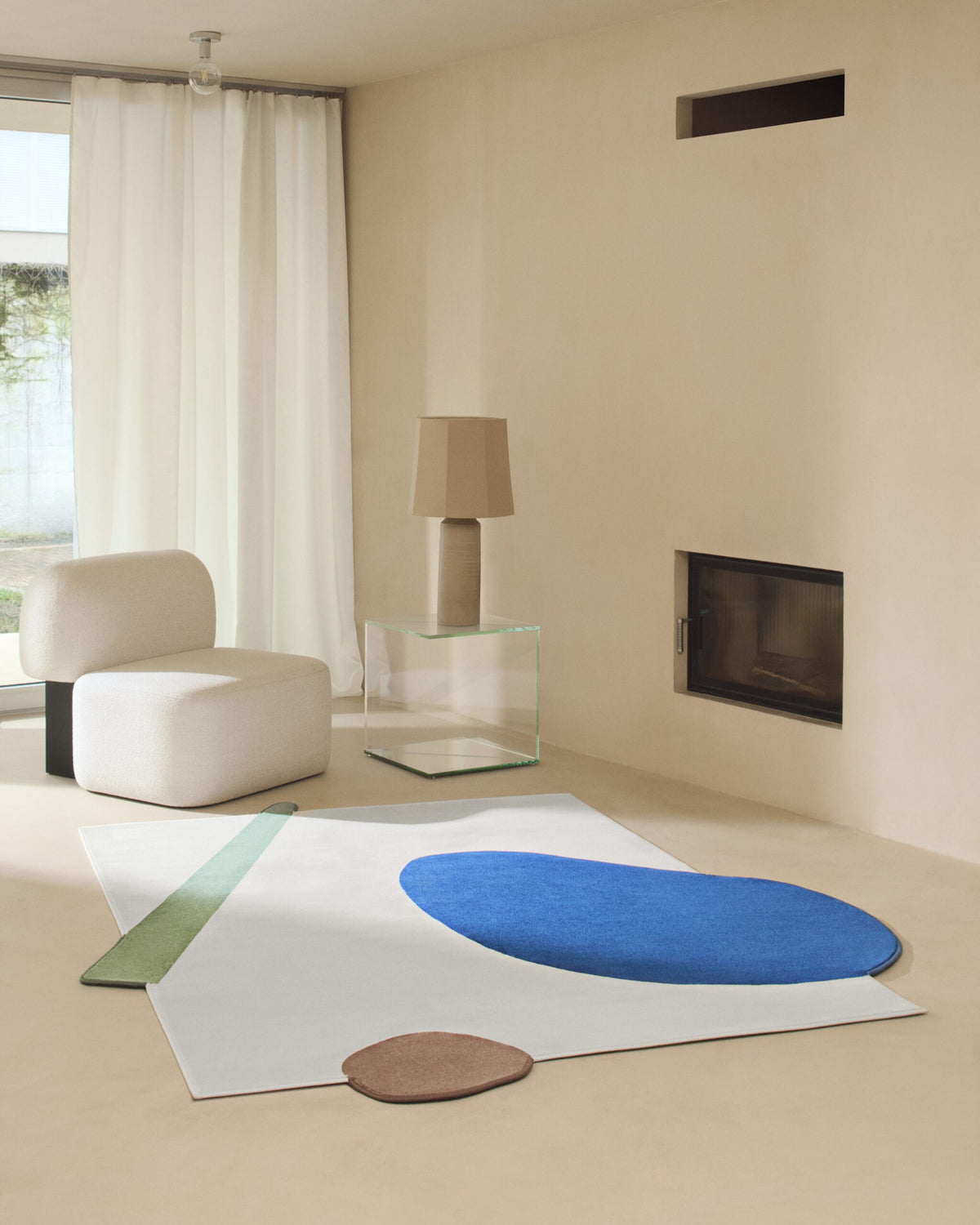Yemeni Lounge Chair in cream in a bright room with a blue abstract rug and fireplace
