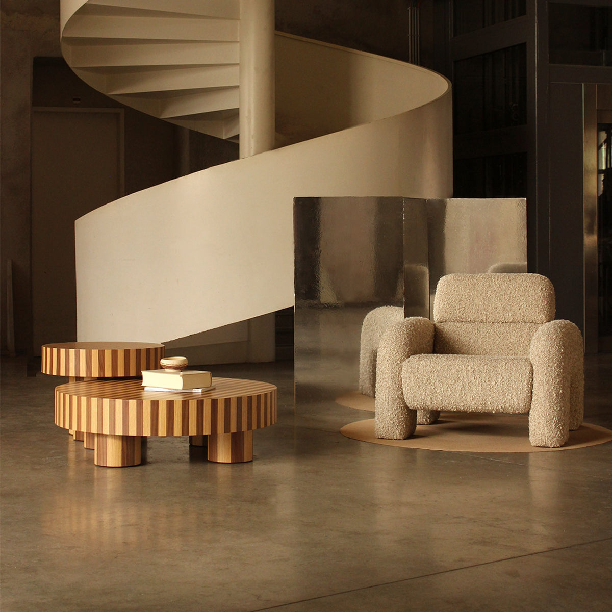 Nusa Side Table as a low centre table near a spiral staircase and boucle armchair