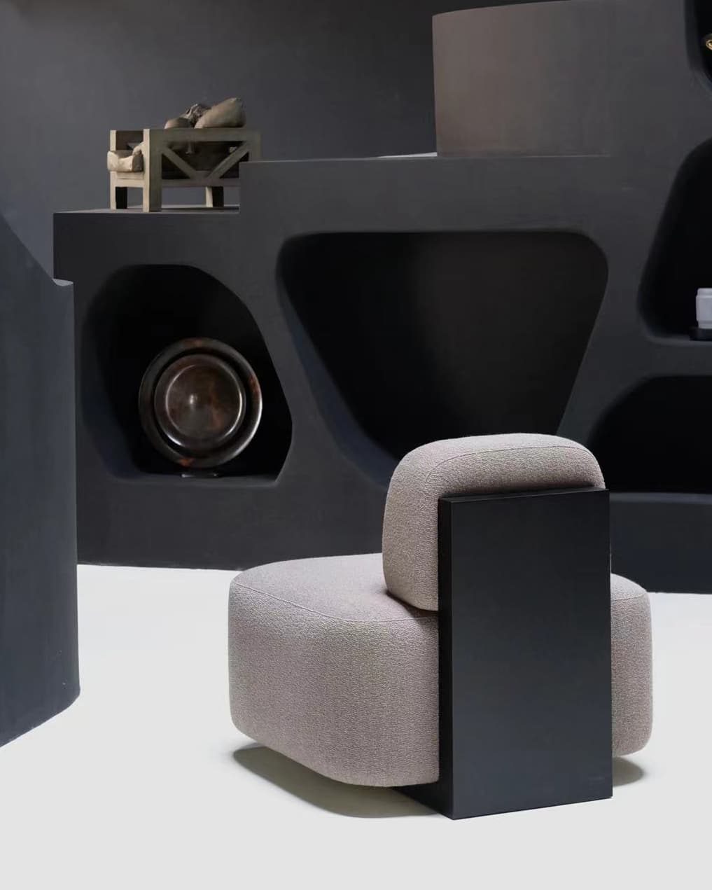 Yoshida Lounge Chair in lilac grey with black side panel against dark shelving